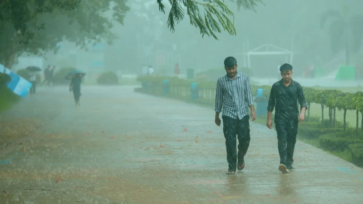 सांकेतिक तस्वीर: बारिश में लोग पार्क में चल रहे हैं