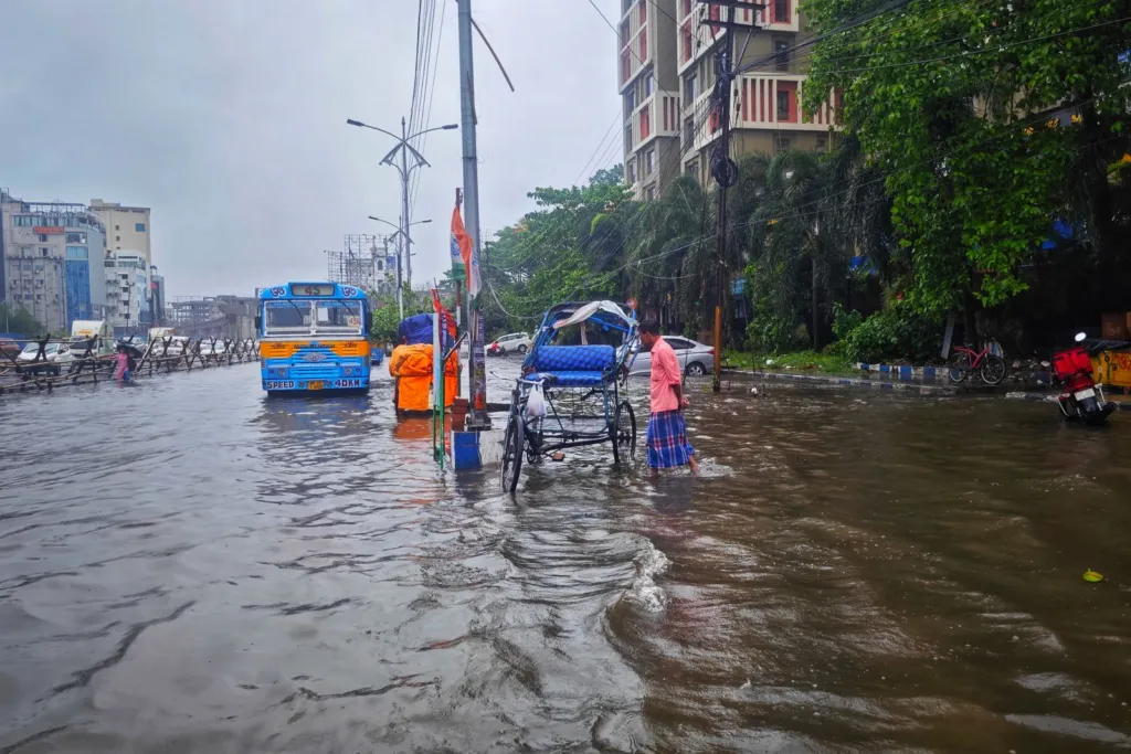 सांकेतिक तस्वीर: बारिश के दौरान जलजमाव वाली सड़क पर वाहन और लोग